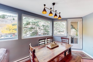 Enjoy meals in this dining area with a view of the surrounding landscape, featuring a wooden table and chairs.