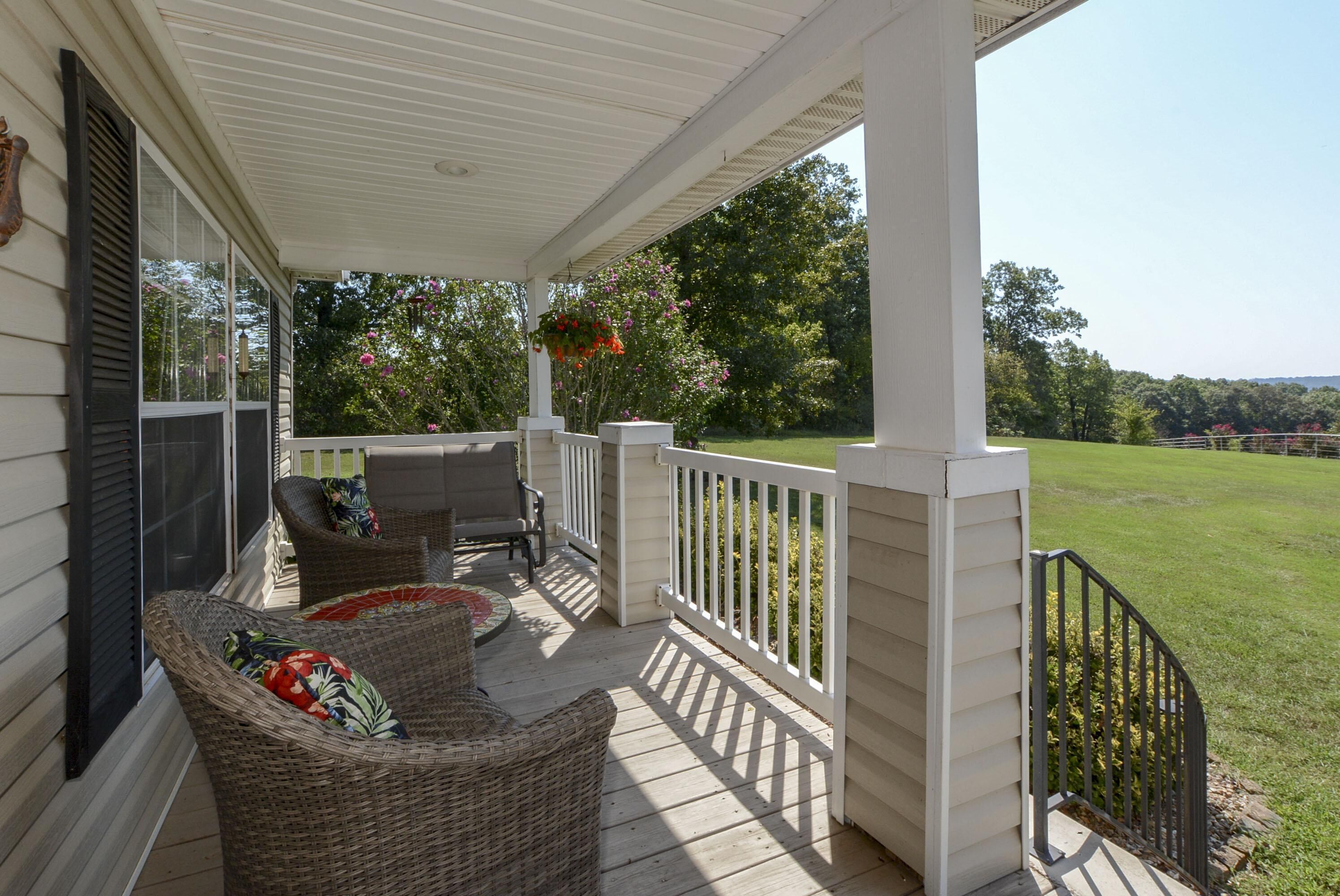A covered porch with wicker furniture and hanging flower baskets.