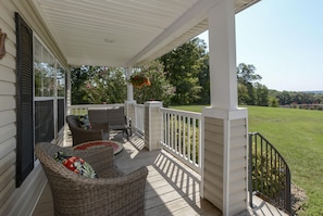 A covered porch with wicker furniture and hanging flower baskets.