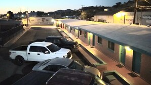 A row of single-story buildings with a flat roof, likely a motel or small hotel, with a parking lot in front.