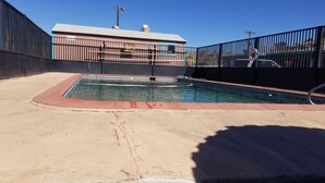 A rectangular swimming pool with a tiled edge, surrounded by a concrete deck.