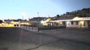 A parking lot with a row of buildings, including a bus stop and a small structure with lights.