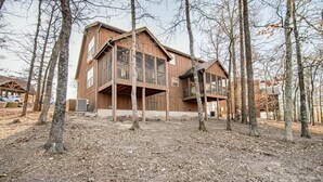 A large wooden house with multiple floors and balconies, surrounded by trees. - Bear Cabin Getaway (Reeds Spring)