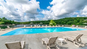 A swimming pool with lounge chairs and umbrellas, surrounded by a fence and greenery. - Bear Cabin Getaway (Reeds Spring)