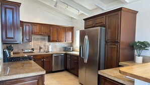 Una cucina moderna con mobili in legno, elettrodomestici in acciaio inossidabile e un piano di lavoro in granito.
