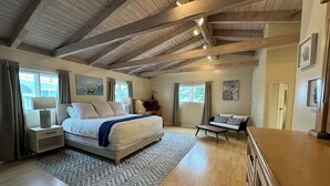 Una camera spaziosa con un letto grande, un soffitto in legno e vista sull'esterno dalla finestra.