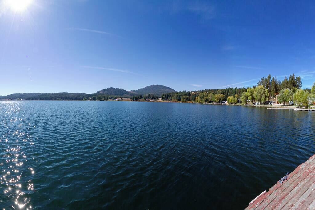 Un lago tranquillo con una montagna sullo sfondo e un molo di legno che si protende nell'acqua.