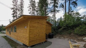Une petite cabane en bois avec un porche, entourée d’arbres.