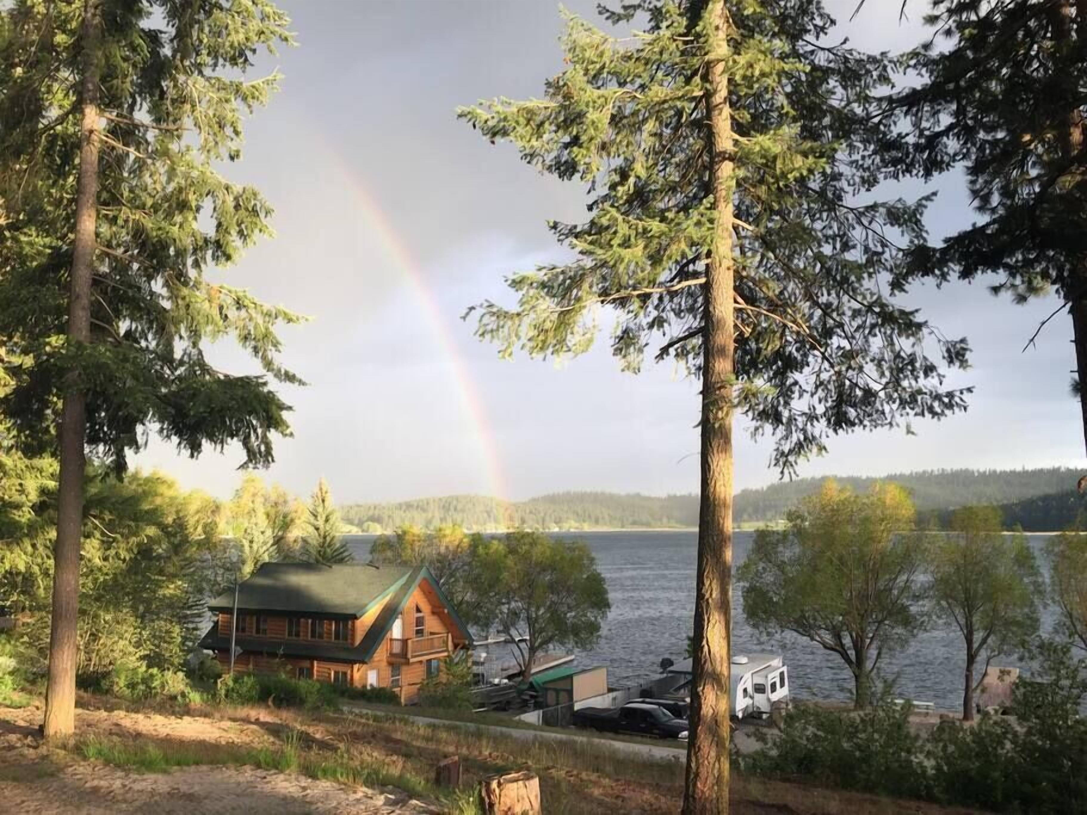 Eine Hütte mit einem grünen Dach, umgeben von Bäumen und einem See.