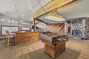 Ein Raum mit einer Holztresore, einem Kicker, einem Steinkamin und einem Essbereich mit Stühlen und einem Tisch.