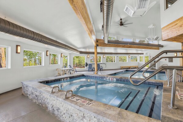 Ein Schwimmbecken mit deutlichen Bahnen, einer Holzbeschichtung und Blick auf Bäume durch große Fenster.