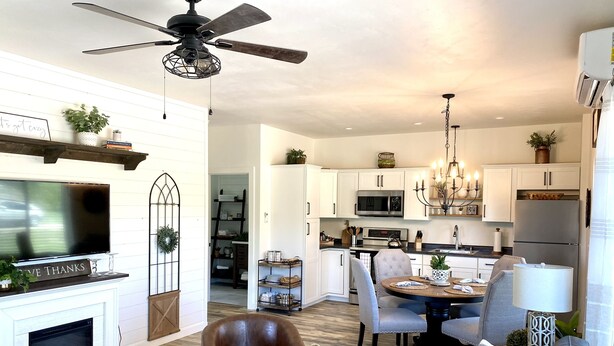 Una sala de estar moderna con chimenea, televisor y ventilador de techo.