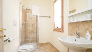 A bathroom with a glass-enclosed shower, a toilet, a sink, and a mirror. - Villino Rosmarino - Cignella Resort Toscana (Toscana)