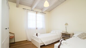 A bedroom with two beds, a bedside table with a lamp, a wardrobe, and a window with curtains. - Villino Rosmarino - Cignella Resort Toscana (Toscana)