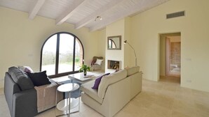 A modern living room with a large window, a sofa, a coffee table, and a lamp. - Villino Rosmarino - Cignella Resort Toscana (Toscana)