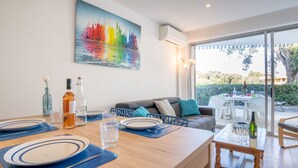 Un coin repas avec une table en bois dressée pour quatre personnes, un canapé et une grande fenêtre.