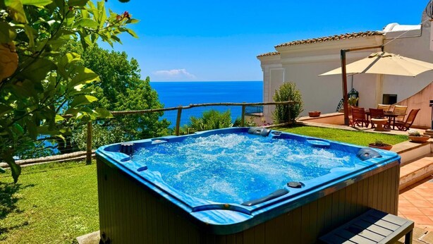 Un jacuzzi dans un jardin, avec vue sur la mer.