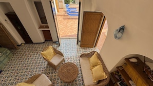 Une pièce dotée d’un sol à motifs, de meubles en osier et donnant sur un espace extérieur avec une piscine.