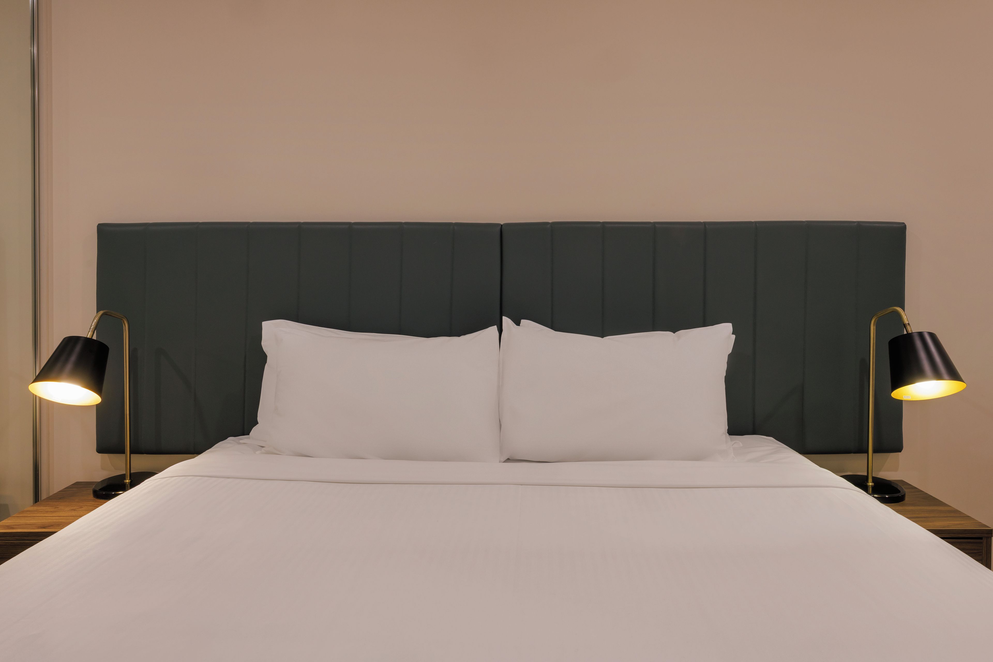 A bed with a dark headboard, two bedside lamps, and white bedding.