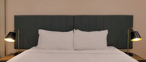 A bed with a dark headboard, two bedside lamps, and white bedding.