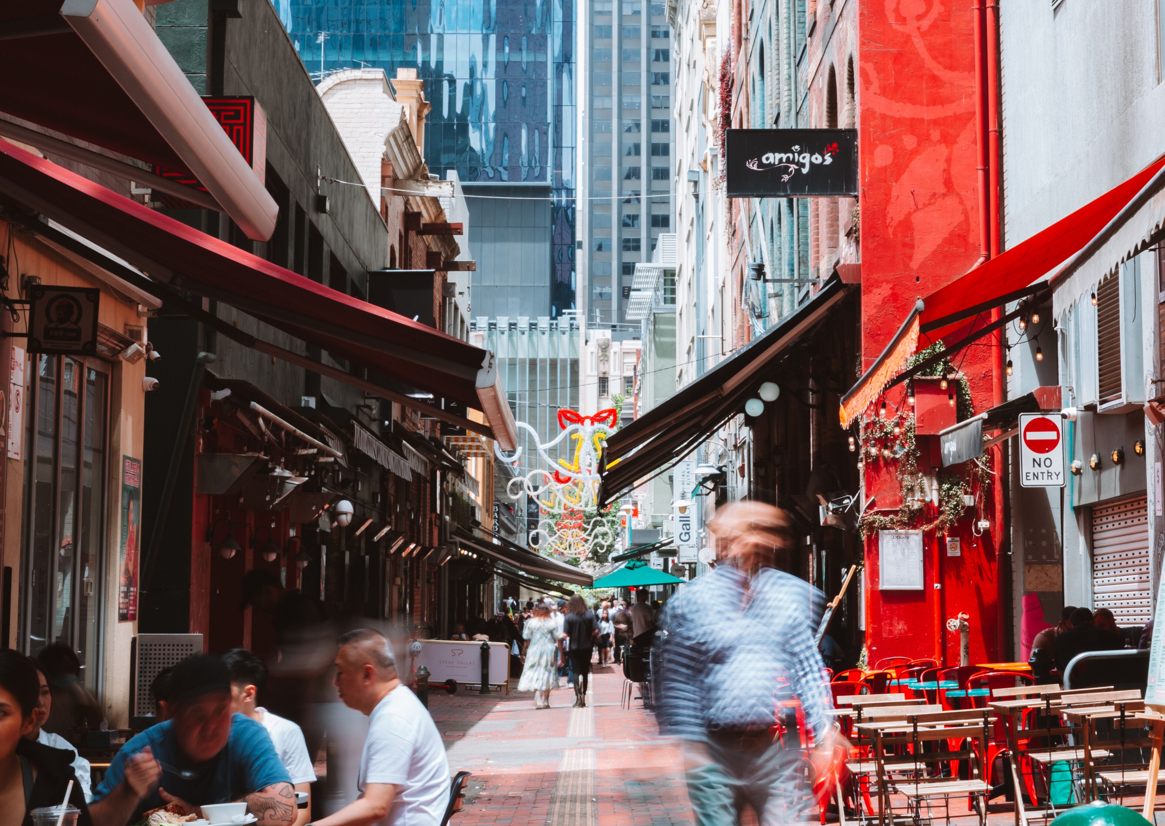 A narrow street with outdoor seating, traditional architecture, and a 'NO ENTRY' sign.