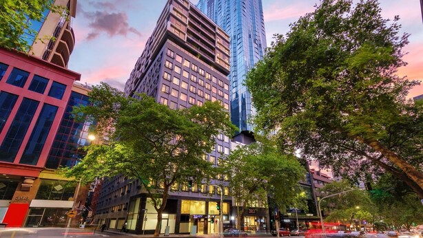 A cityscape with modern buildings, including a prominent skyscraper and a building with a 'BRADY' sign. - Brady Apartment Hotel Hardware Lane (Melbourne)