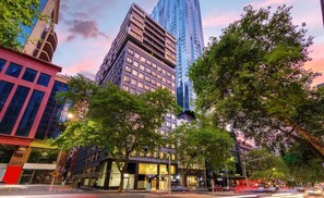 A cityscape with modern buildings, including a prominent skyscraper and a building with a 'BRADY' sign. - Brady Apartment Hotel Hardware Lane (Melbourne)