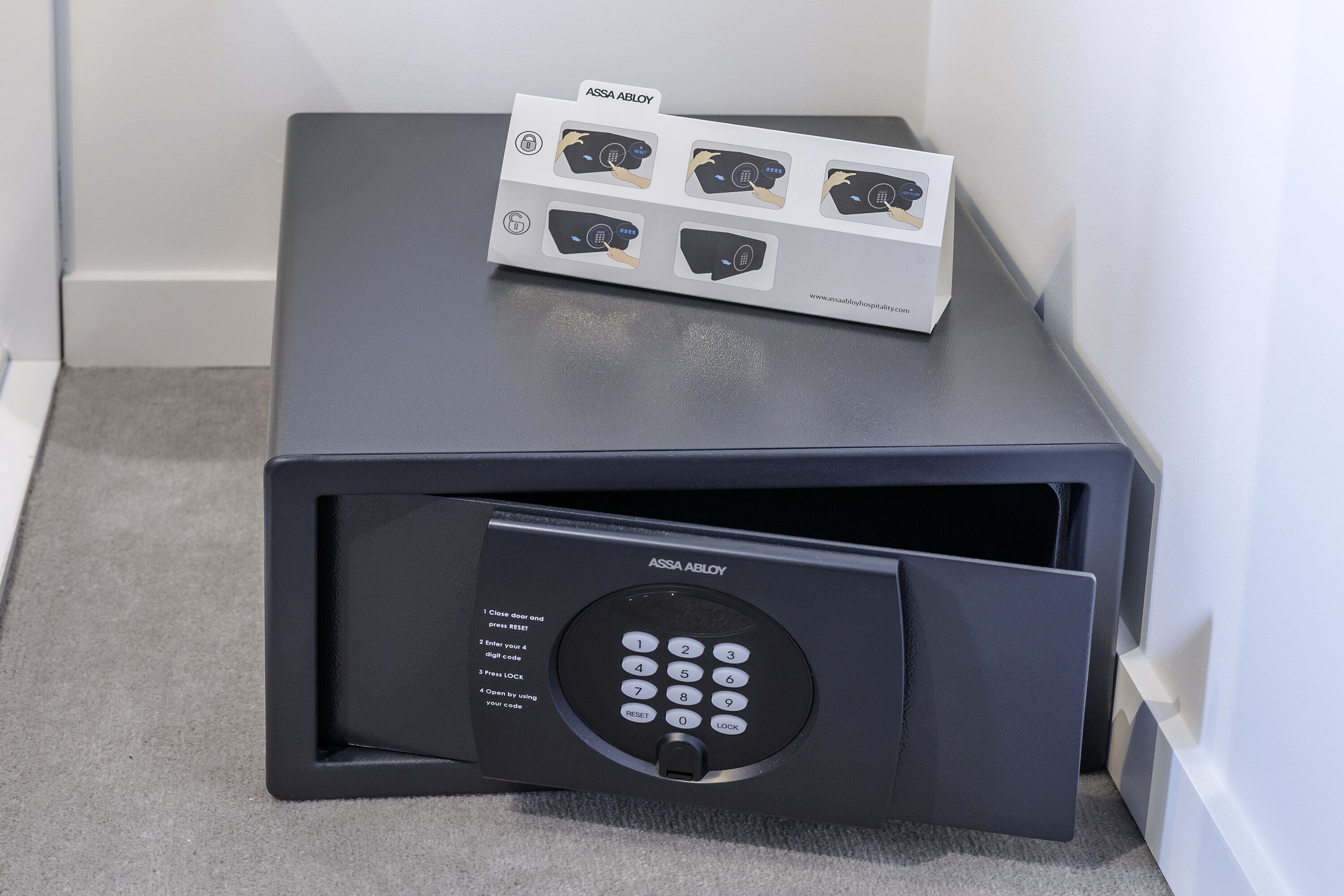 A black safe with a keypad and a set of keys on top.