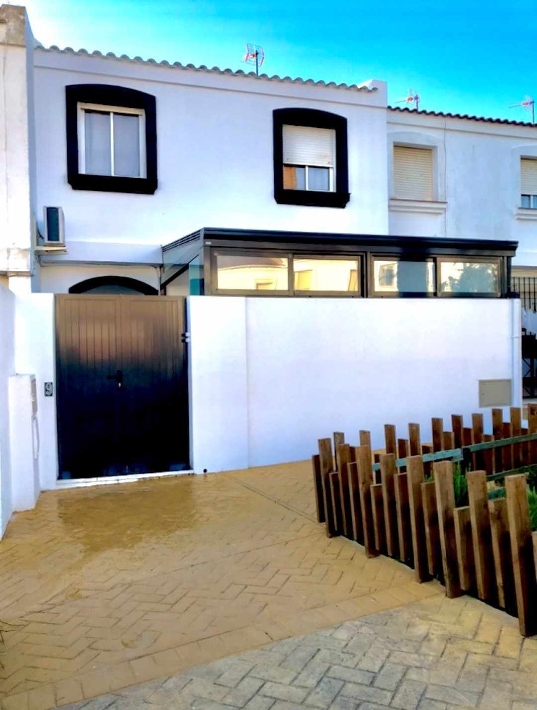 A modern building with a white facade, black-framed windows, and a gated entrance.