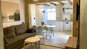 A modern living room with a sofa, a small table, and a dining area with chairs. There is a kitchen visible in the background. - LAS GAVIOTAS 9A APARTMENT (Tarifa)