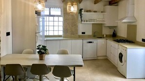 A modern kitchen with white cabinetry, a built-in dishwasher, a washing machine, and pendant lighting. - LAS GAVIOTAS 9A APARTMENT (Tarifa)