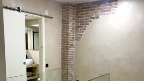 A modern interior with a glass railing, a brick accent wall, and a staircase leading to a lower level. - LAS GAVIOTAS 9A APARTMENT (Tarifa)