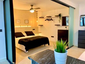 A modern bedroom with a bed, a ceiling fan, a bedside table, and a potted plant. - LAS GAVIOTAS Apartment 9B (Tarifa)