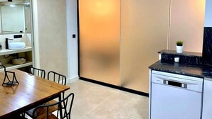 A modern kitchen with a wooden dining table, a built-in oven, and a black countertop. - LAS GAVIOTAS 9B APARTMENT (Tarifa)