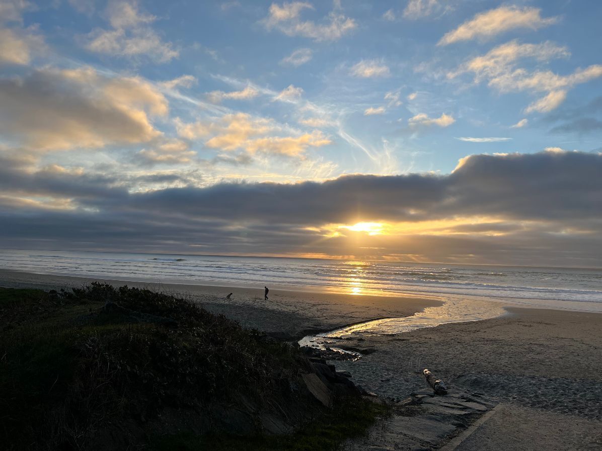 Une plage au coucher du soleil, avec un ciel dégagé et une mer calme.