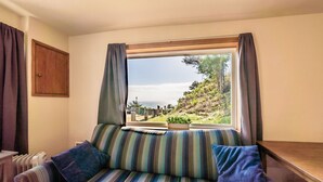 A room with a striped sofa, a wooden table, and a window with curtains.