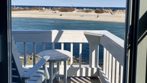 Una terraza de madera con barandillas blancas que da a una playa.