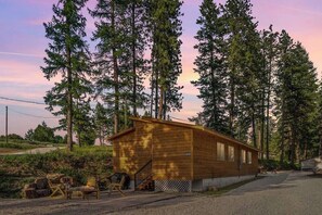 Una cabana de fusta amb un porxo, envoltada d'alzines altes.