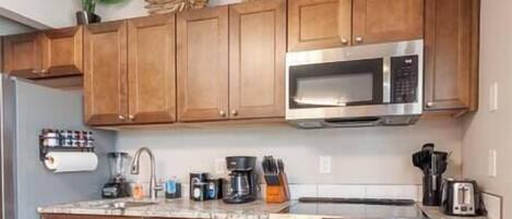 A modern kitchen with wooden cabinets, stainless steel appliances, and a black rug.