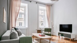 A modern living room with a sofa, a coffee table, a TV, and a chair. - Exclusive Kohlmarkt 1 BR w/ Elevator, walk to Metro U1, U3, by Blueground (Vienna)