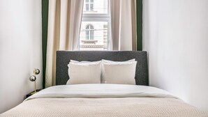 A neatly made bed with a grey headboard, white pillows, and a white duvet. - Exclusive Kohlmarkt 1 BR w/ Elevator, walk to Metro U1, U3, by Blueground (Vienna)
