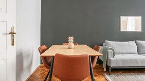 A dining area with a wooden table and chairs, a grey sofa, and a framed picture on the wall. - Exclusive Kohlmarkt 1 BR w/ Elevator, walk to Metro U1, U3, by Blueground (Vienna)