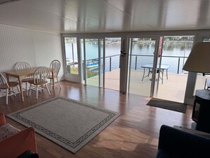 A room with a wooden floor, a dining table with chairs, a large window, and a view of a body of water. - River Front Property  (La Crosse)