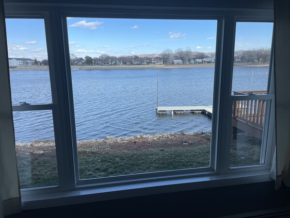 A view from a window overlooking a lake with a dock and a grassy area in the foreground. - River Front Property (La Crosse)