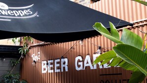 A corrugated metal wall with the text "The Beer Garden" and "Collier's" visible. There are outdoor tables and chairs under a black umbrella. - Colliery Inn, Wallsend (Wallsend)