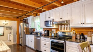 A kitchen with white cabinets, stainless steel appliances, and a wooden ceiling. - Cabin By The Creek! Inground Pool! Spa! (Dayton)