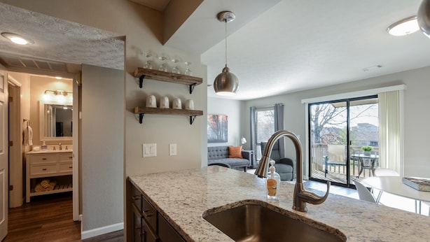 A modern kitchen with a granite countertop, stainless steel sink, and pendant lighting. - Bentley's Bungalow (Branson)