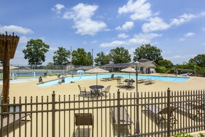 A pool area with lounge chairs and umbrellas, surrounded by a fence. - Bentley's Bungalow (Branson)