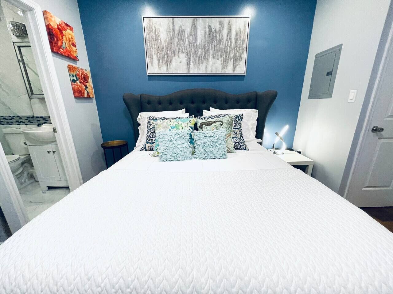 Ein Schlafzimmer mit einem großen Bett, einem dunklen Kopfteil und einer blauen Akzentwand.