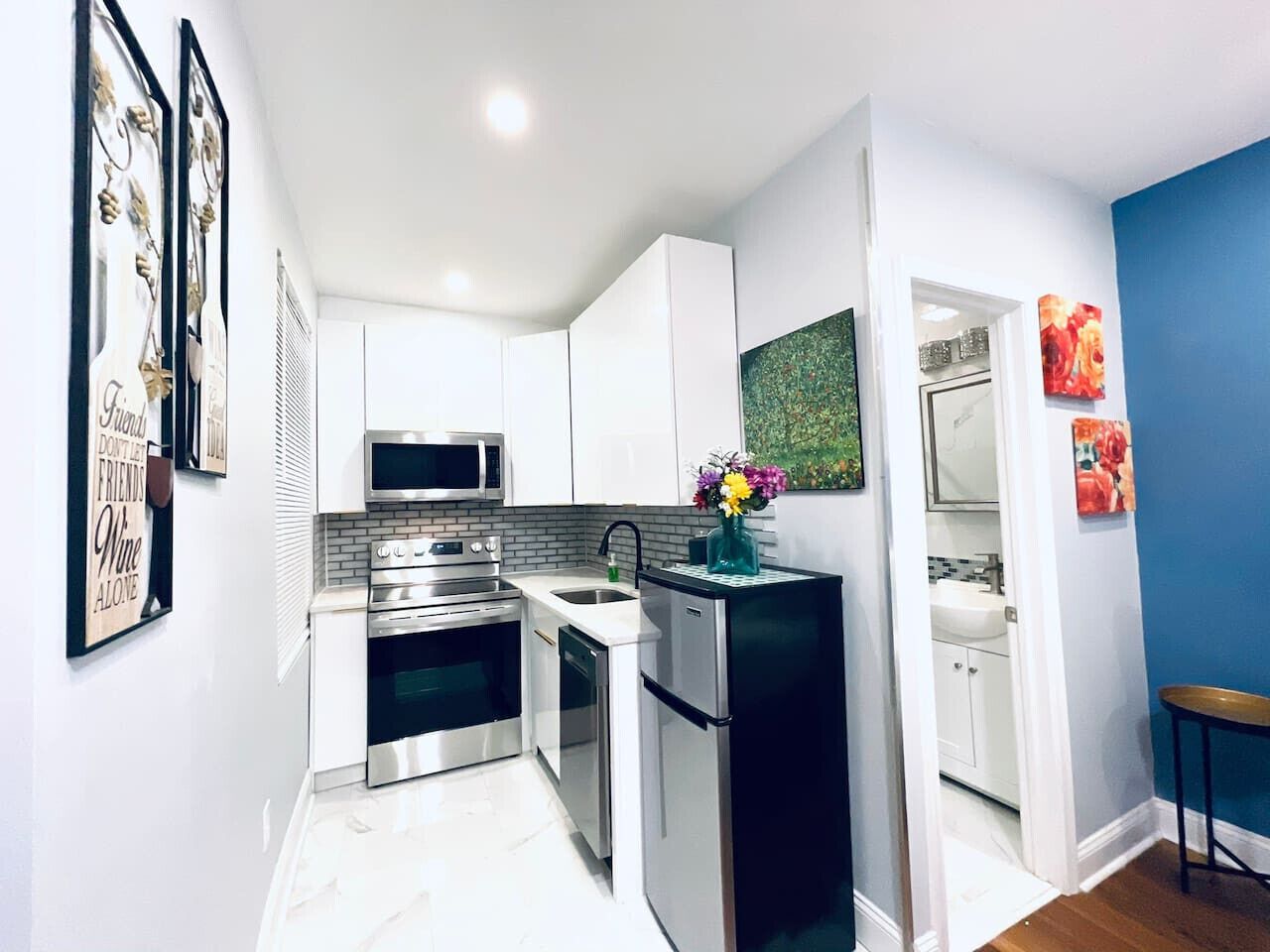 A modern kitchen with white cabinets, stainless steel appliances, and a black refrigerator.